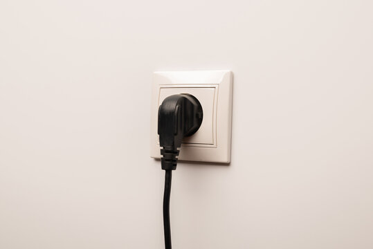 Power socket with inserted plug on white wall, space for text. Electrical supply