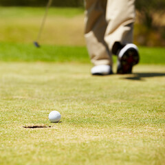 Golf, ball and hole on a green in summer for sports, recreation or leisure closeup for hobby. Grass, ground or field with a golfer walking on a course during a game of competition or training