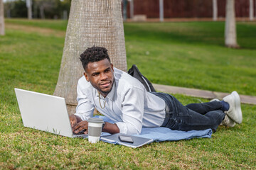 Fototapeta premium An African-American man working on his laptop while on the park floor.