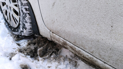 Car wheel on dirty messy snow. Mud, salt and chemicals on winter road. Ecology in city. Protection...