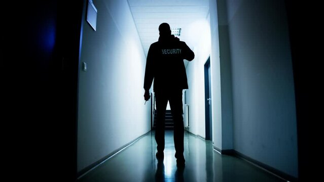 Male Security Guard Holding Flashlight Standing In Corridor