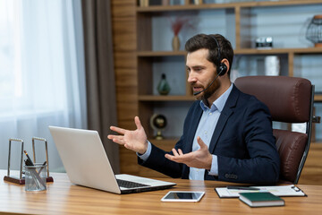 Fototapeta na wymiar Mature businessman with headset engaged in an online conference call while working remotely from a home office setup.