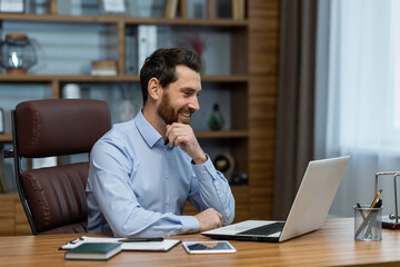 Smiling mature businessman at home office, engrossed in productive work on his laptop, exuding...