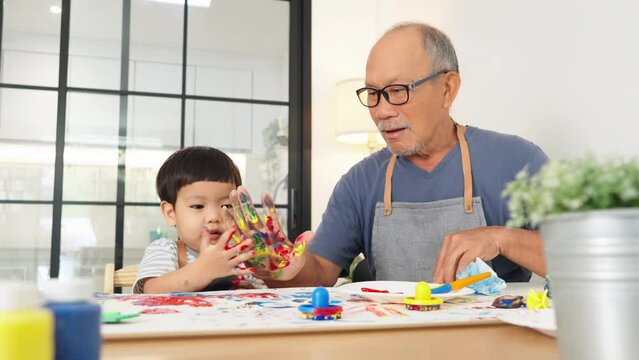 Grandfather and grandson enjoying a playful moment with colorful handprints during arts and crafts time