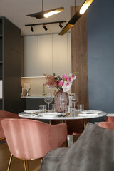 Dining table in the kitchen with pink flowers bouquet in the vase