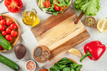 Fresh ingredients for cooking salad and empty wooden cutting board . Healthy clean eating, vegetarian food and diet nutrition concept