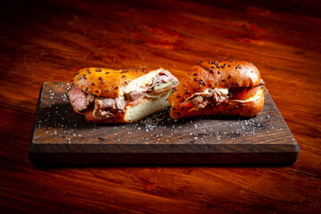 Sandwich with roast beef, tomato and cucumber. On a wooden table.