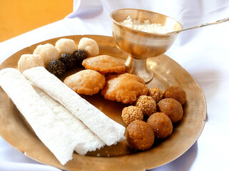Assamese traditional food items like pitha, laddu, doi sira with assamese gamosa background with japi motifs