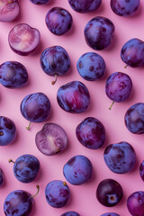Flat lay of plums on a pastel pink background.