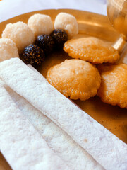 Assamese traditional food items like pitha, laddu, doi sira with assamese gamosa background with japi motifs
