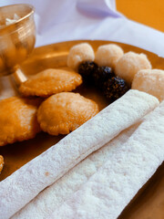 Assamese traditional food items like pitha, laddu, doi sira with assamese gamosa background with japi motifs