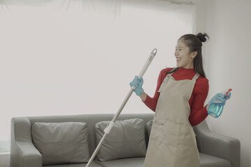 Asian woman doing housework wearing an apron cleaning the wooden floor in the living room The housekeeper is busy doing housework, wiping the dirty cooking counter. For housework or housework