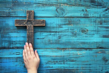 Hand holding cross on blue wooden background concept of faith and Easter.