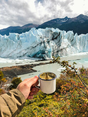 A hand holding an Argentine mate, with the Perito Moreno glacier in the background.
View of the...