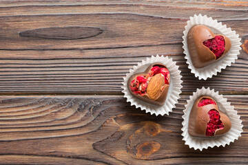 chocolate sweets in the form of a heart with fruits and nuts on a colored background. top view with space for text, holiday concept