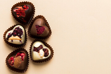 chocolate sweets in the form of a heart with fruits and nuts on a colored background. top view with space for text, holiday concept