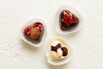 chocolate sweets in the form of a heart with fruits and nuts on a colored background. top view with space for text, holiday concept