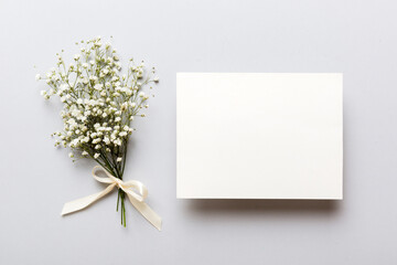 Wedding mockup with white paper list and flowers gypsophila on colored table top view flat lay....