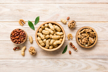 Walnut kernel halves with peanut, in a wooden bowl. Close-up, from above on colored background. Healthy eating groundnut concept. Super foods with copy space