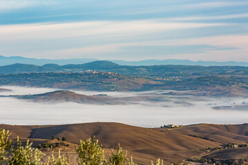 Elevated autumnal scenery panoramic perspective over Tuscany, Italy, valleys with thick fog. Amazing travel and tourist Italian destination.