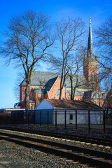 Fototapeta na wymiar Church and bare trees along the train tracks, winter travel landscape photo in Wallingford, Connecticut, USA