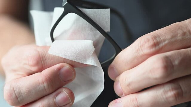 Man cleaning and wiping eyeglasses, close up of hands