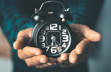 Time management concept. Man hands holding Black retro alarm clock. Time to wake up for the morning...