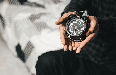 Time management concept. Man hands holding Black retro alarm clock. Time to wake up for the morning...