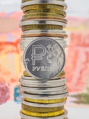 1 ruble coin on the background of a stack of coins and banknotes