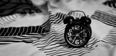 Deadline and Time management concept. Black retro alarm clock on bed. time to wake up for the...