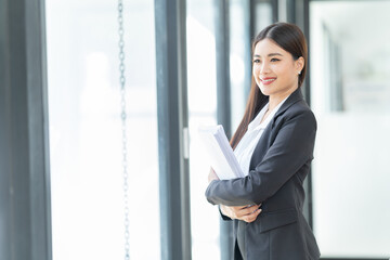 Sharing good business news. Attractive young businesswoman talking on the mobile phone and smiling while sitting at her working place in office and looking at laptop PC.