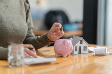 Closeup of  woman hand putting money coin into piggy bank for saving money. saving money.