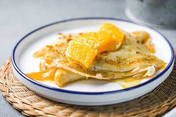 Delicious crepes suzette with orange syrup on plate