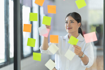 Sharing good business news. Attractive young businesswoman talking on the mobile phone and smiling while sitting at her working place in office and looking at laptop PC.