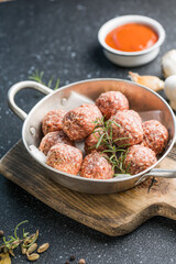 Raw meatballs in pan on the wooden cutting board
