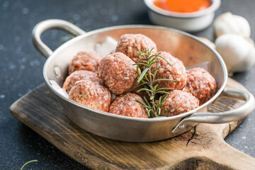 Raw meatballs in pan on the wooden cutting board