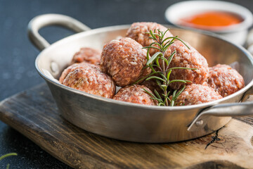 Raw meatballs in pan on the wooden cutting board