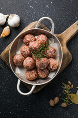 Raw meatballs in pan on the wooden cutting board
