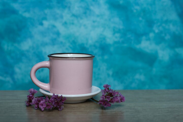 Pink coffee cup on wooden table and blue background. Copy space.