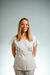 Pretty woman on a grey background with her hands behind her back