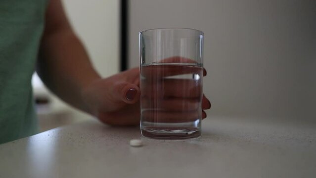 Dietary supplement Caucasian young woman hand holding medical pill capsule, take or eat vitamin. Sick female taking medicines drinking with water at home, pharmacy and healthcare. Close up High