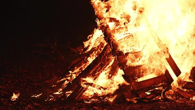 Bonfire burning at night, bright orange flames of fire