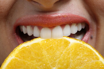 close up of a woman eating a slice of orange