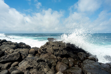 beach landscape with the sea and waves and cliffs of the coasts of the Galapagos Islands in the Pacific Ocean with blue and green water and volcanic rocks