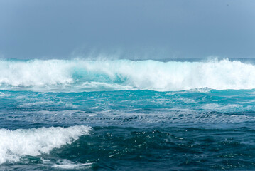 beach landscape with the sea and waves and cliffs of the coasts of the Galapagos Islands in the Pacific Ocean with blue and green water and volcanic rocks
