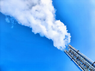 Air pollution by smoke coming out of factory chimney. White clouds of smoke against a blue sky...