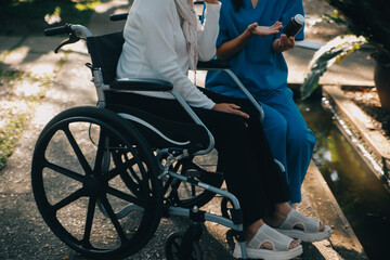 Obraz premium nurse with elderly man in wheelchair at park