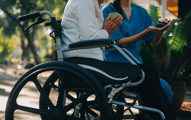 Obraz premium nurse with elderly man in wheelchair at park