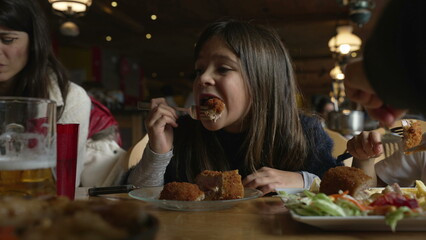 Cozy Dining Delight - Little Girl Enjoying Cordon Bleu Chicken at Family Mealtime in Wooden Interior Diner, people eating food at restaurant
