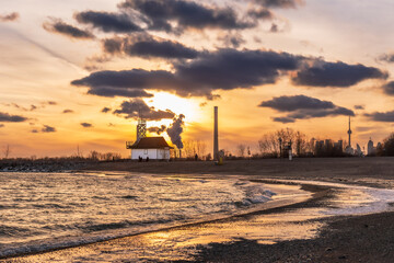 sunset on icy beach in winter with dramatic clouds and  downtown skyline in distant background shot...